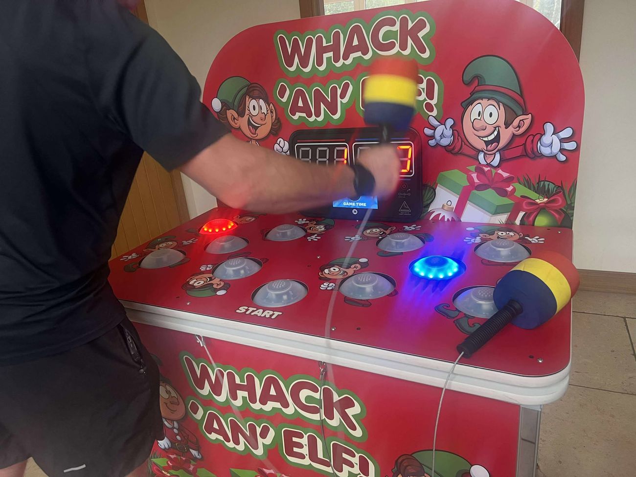 Player mid-swing with a mallet as the Whack an Elf domes light up and the countdown timer runs