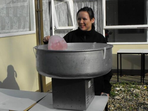 a lady making some candy floss on a large candy floss maker