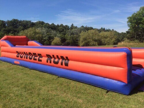 red and blue bungee run inflatable in a field