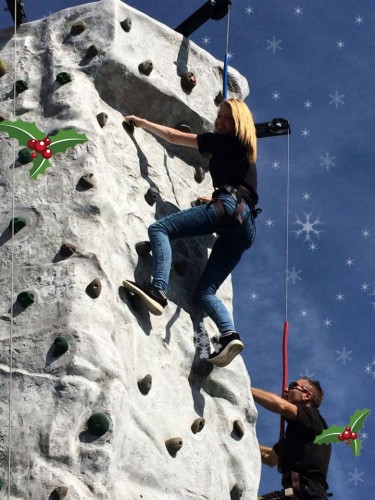 a girl smiling as she climbs the mobile rock climbing wall